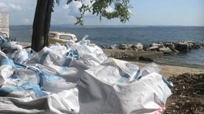Vreče z morskimi naplavinami in odpadki v kriškem portiču čakajo na odvoz